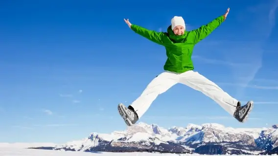 person doing a star jump with a background of perfect clear blue sky