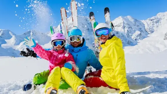 three people in very bright ski clothes sat on the snow